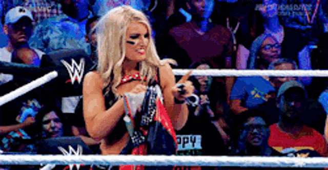 a woman is standing in a wrestling ring with a w on her shirt