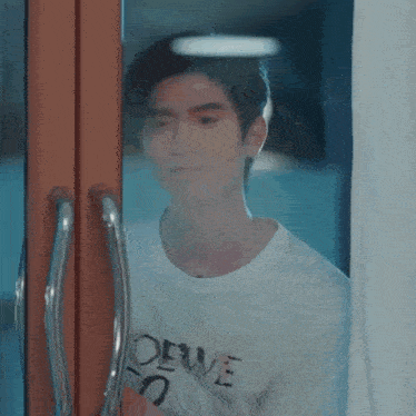a man in a white shirt is standing in front of a window .