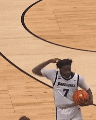 a man in a providence jersey holds a basketball in his hands