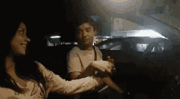 a man and a woman are holding hands while sitting in a car .