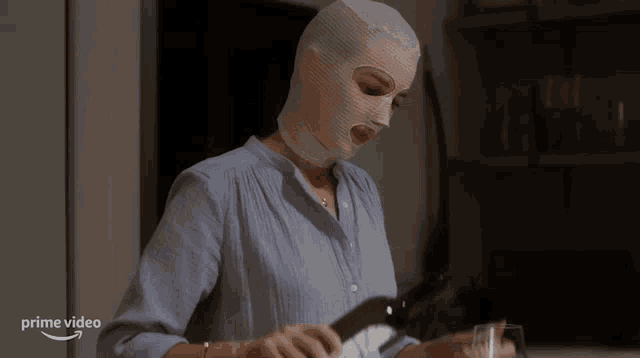 a woman wearing a ski mask is holding a glass of wine