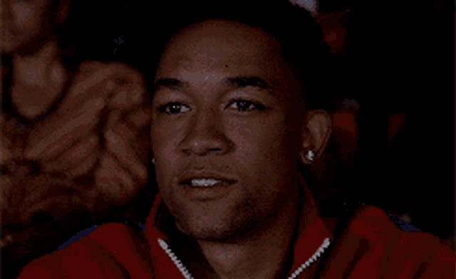 a man in a red jacket with pearls on his ear is watching a movie
