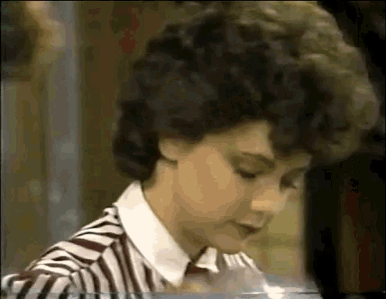 a woman with curly hair is wearing a striped shirt and a white collared shirt .