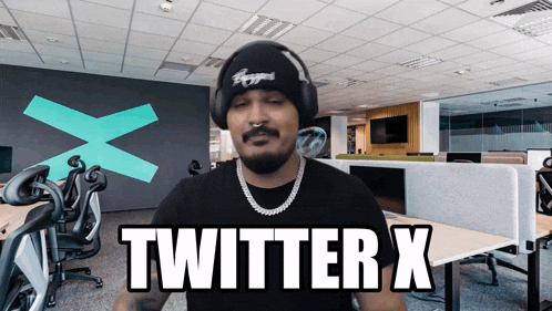 a man wearing headphones and a beanie says twitter x in an office