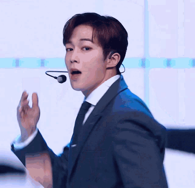 a man wearing a suit and tie with a microphone around his neck