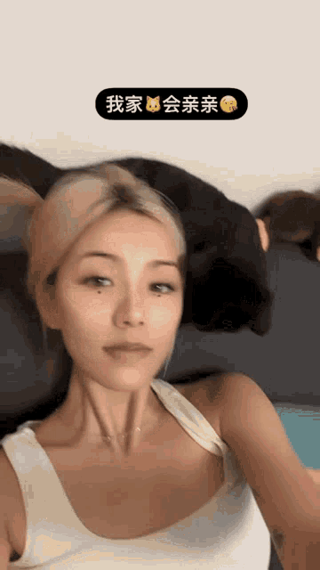 a woman in a white tank top is taking a selfie with chinese writing on the bottom