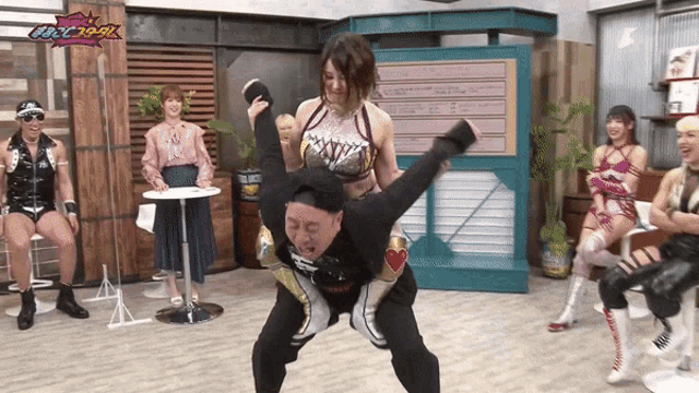 a man is carrying a woman on his back in a room with a sign that says ' tokyo ' on it