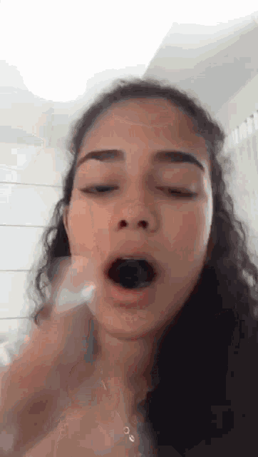 a close up of a woman 's face with her mouth open and a black object in her mouth .