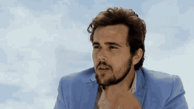 a man with a beard is wearing a light blue suit