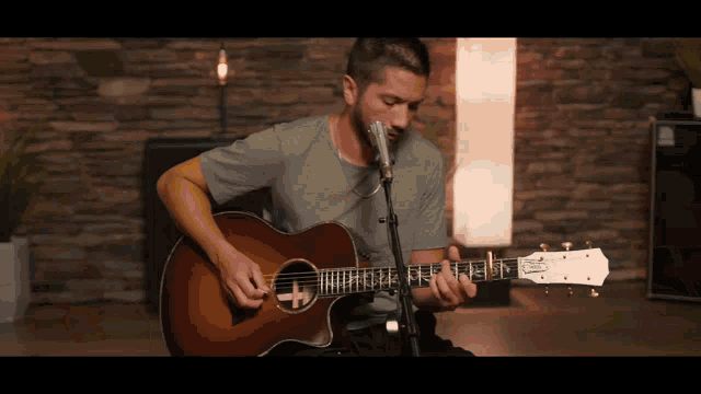 a man is playing an acoustic guitar in front of a microphone