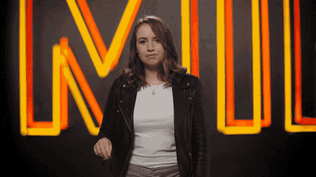 a woman in a leather jacket stands in front of a sign that says lnwl