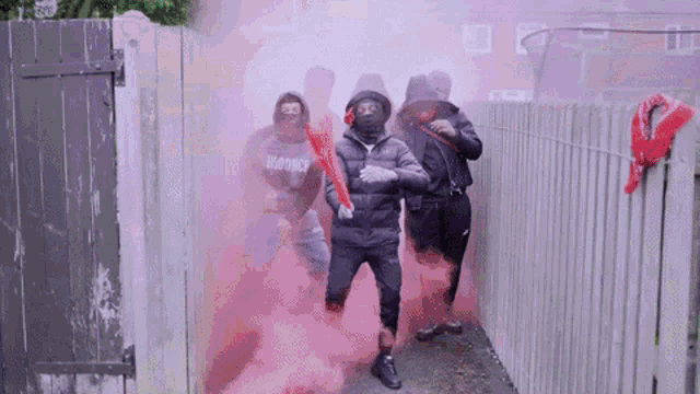 a group of men wearing masks are walking through a smoke filled alleyway ..