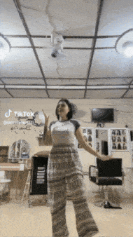 a woman dancing in a room with a sign that says tiktok