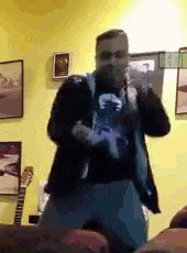a man is standing in front of a microphone in a room with a guitar in the background .