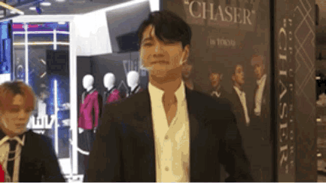 a man in a suit and white shirt is standing in front of a sign that says chasers .