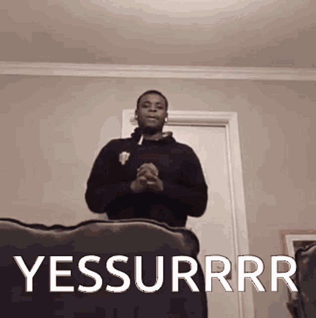 a man is sitting on a couch with the words yessurrr written on it