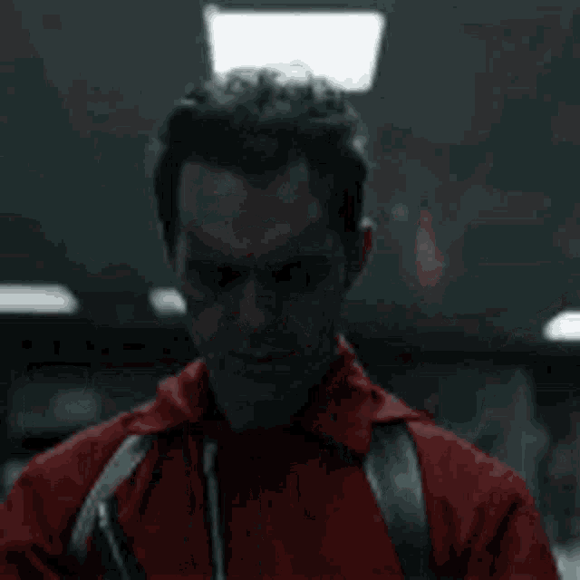 a group of people in red jumpsuits are standing next to each other holding guns in a dark room .