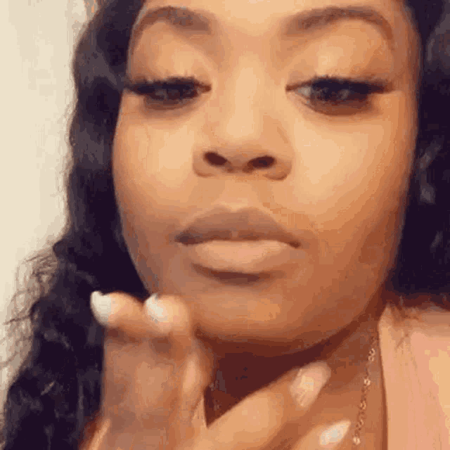 a close up of a woman smoking a cigarette while wearing a pink shirt .