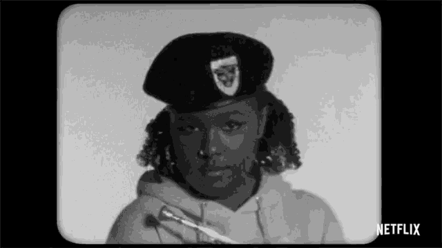 a black and white photo of a woman wearing a beret holding a trumpet