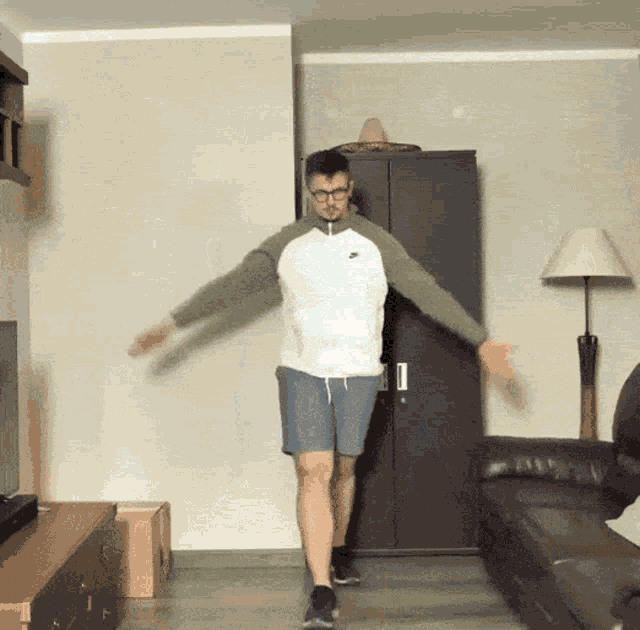 a man is dancing in a living room in front of a couch and a lamp