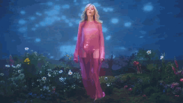 a woman in a purple dress is standing in a field of flowers