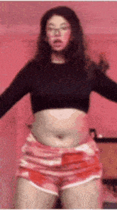 a woman in a crop top and shorts is dancing .