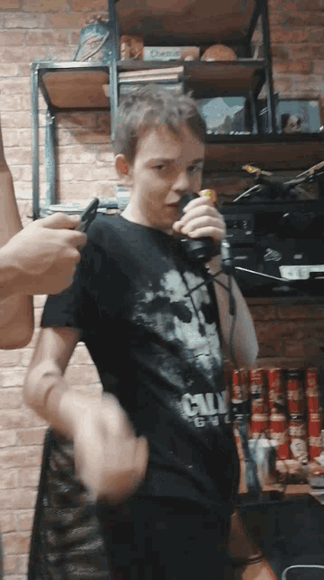 a boy wearing a call of duty shirt is holding a controller
