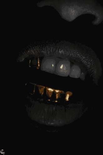 a close up of a person 's mouth with gold grills on
