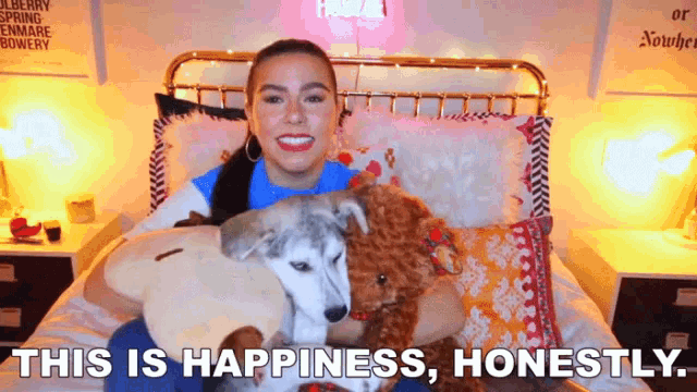 a woman is sitting on a bed holding a stuffed animal and the words " this is happiness honestly " are visible