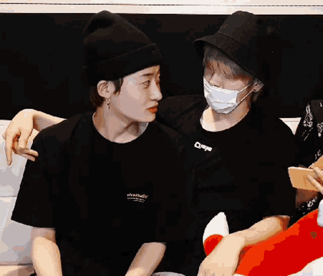 two people sitting next to each other one wearing a mask