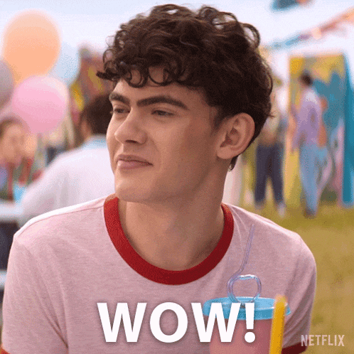 a young man with curly hair is wearing a pink shirt that says wow on it