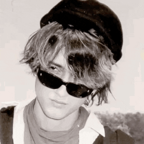 a black and white photo of a young man wearing a hat and sunglasses .