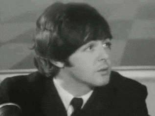 a black and white photo of a man in a suit and tie talking into a microphone