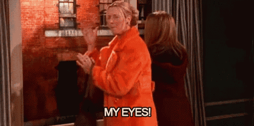 a woman in an orange coat is standing next to a woman in a red coat and says `` my eyes ! ''