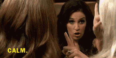 a woman is making a peace sign with her finger while another woman looks on .