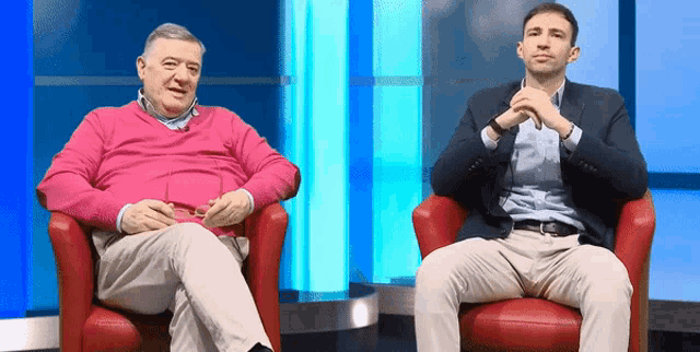 a man in a pink sweater sits next to another man