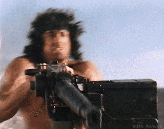 a shirtless man is holding a machine gun with the words vhs ninja on the bottom right