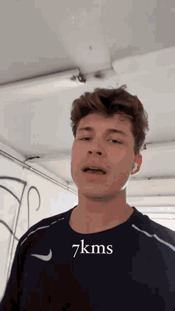 a young man wearing a black shirt with the words 7kms written on it