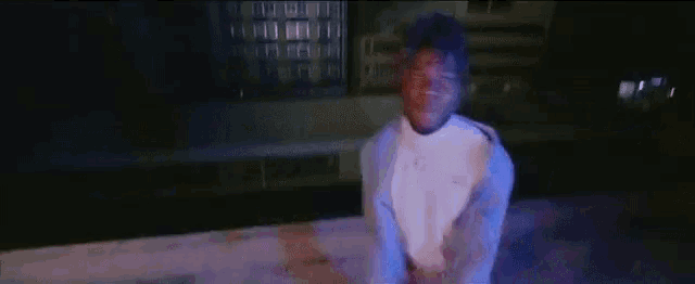 a man in a white shirt and blue jacket is standing on a rooftop at night .