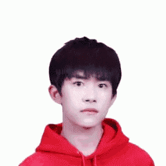 a young man in a red hoodie is pointing at the camera .