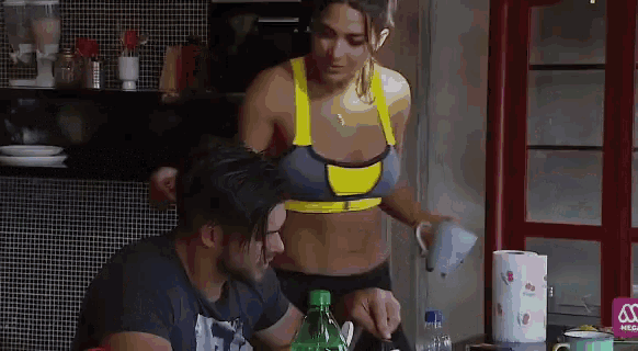 a woman in a sports bra pours a cup of coffee into a man 's cup