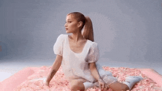 a woman in a white dress is sitting on a bed of petals .