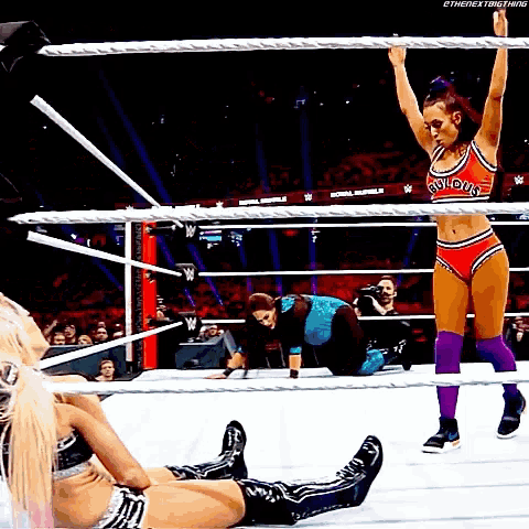 two women are wrestling in a ring and one of them is wearing a red top that says " glorious "