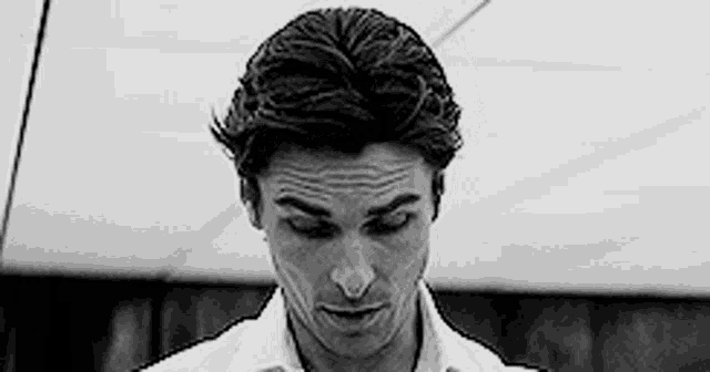 a black and white photo of a man wearing a white shirt and tie .