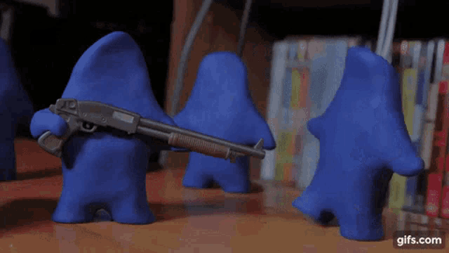 a gif of a blue monster holding a shotgun with the website gifs.com in the lower right corner