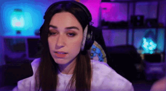 a woman wearing headphones and a white shirt is sitting in front of a computer screen .