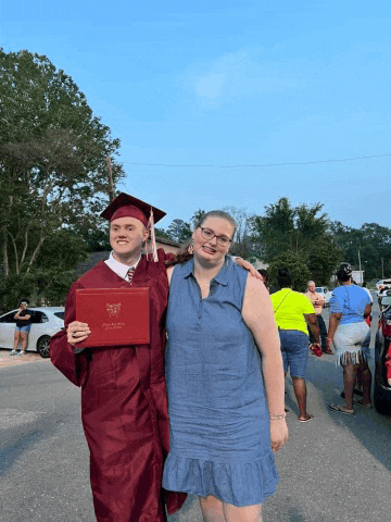 a man in a graduation cap and gown holds up a diploma