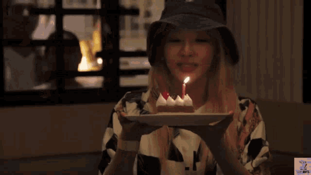 a woman blowing out a candle on a birthday cake with a watermark that says go nuts