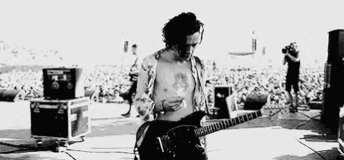 a man is playing a guitar without a shirt on on a stage in front of a crowd .