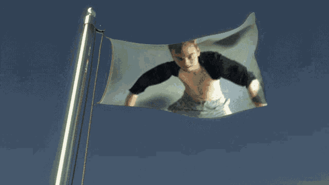 a flag with a picture of a shirtless man flying in the wind